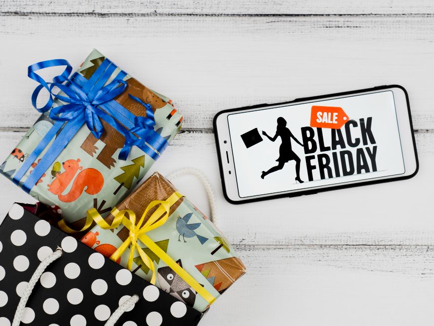 An image of gifts wrapped in wrapping paers and a phone by the side with black friday sale being displayed on it